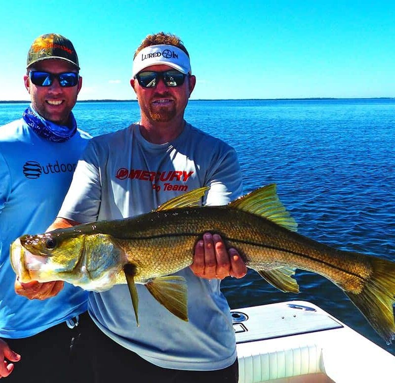 two fisherman holding a snook